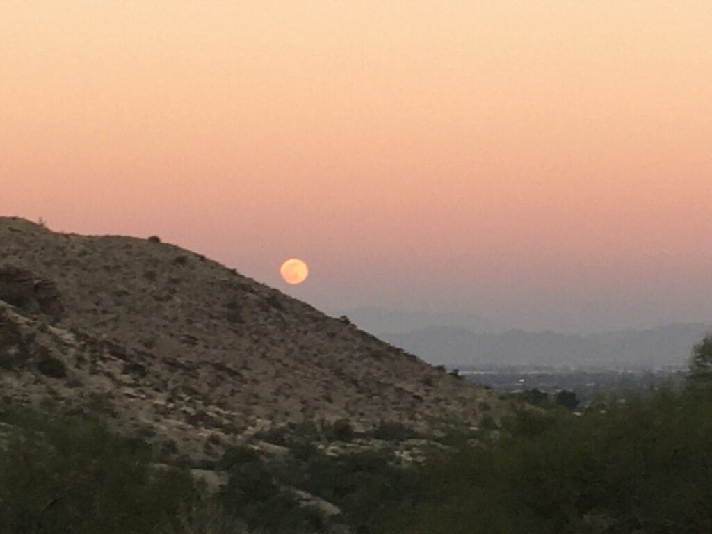 photo of the moon rising over a mountain in a colorful pastel sky