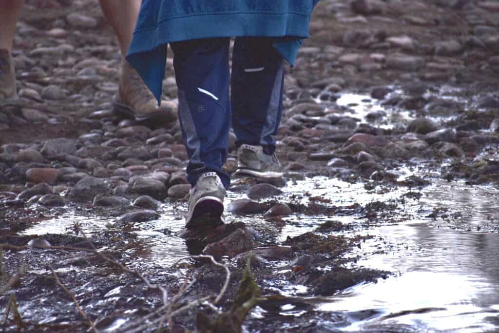 photo of Rocket Kid's feet walking over stones in water. The stones are not out of the water enough to keep his feet dry.
