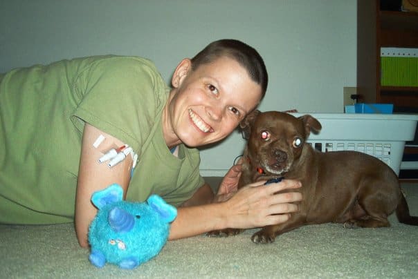 photo of me with a shaved head and a PICC in my arm together with my dog and a dog toy